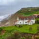 Shocking photos taken today (Thurs) show a three-bedroom house hanging perilously over a cliff edge on the north Norfolk coast after a surge of recent cliff falls. , Trimingham, Norwich Thursday 04 April 2024. Picture by Terry Harris